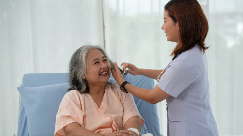Person combing the hair of an elderly hospital patient