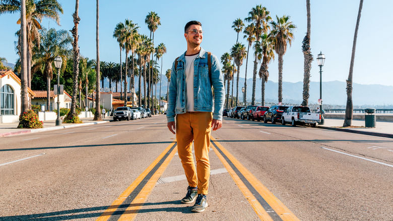 man standing in middle of a California road on sunny day