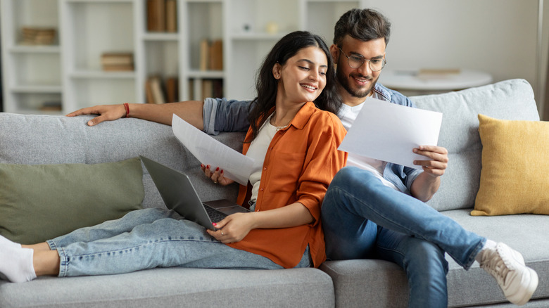 A couple sitting on a couch looking over their credit score.