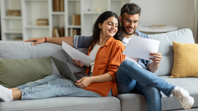 A couple sitting on a couch looking over their credit score.