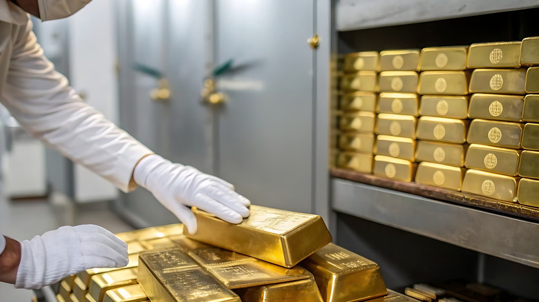 Banker handling gold bars while wearing gloves.