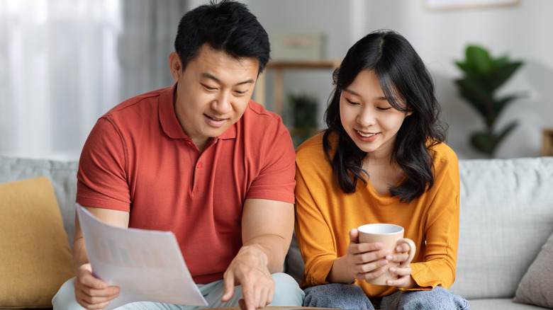 millennial couple sitting at home reading documents