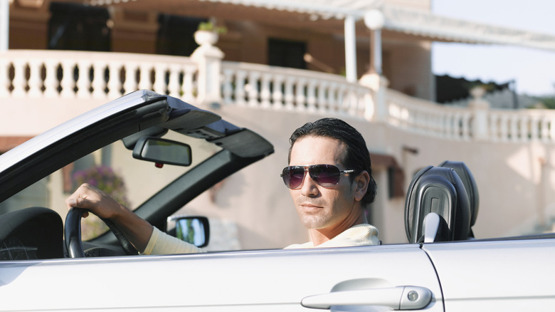 A man smirking in a luxury vehicle