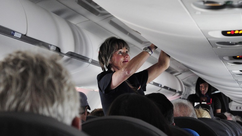an American Airlines flight attendant closes a luggage compartment