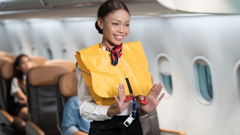 a flight attendant demonstrates an aircraft lifejacket