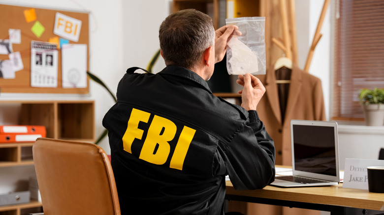 An FBI Special Agent at a desk examining a bag with evidence.