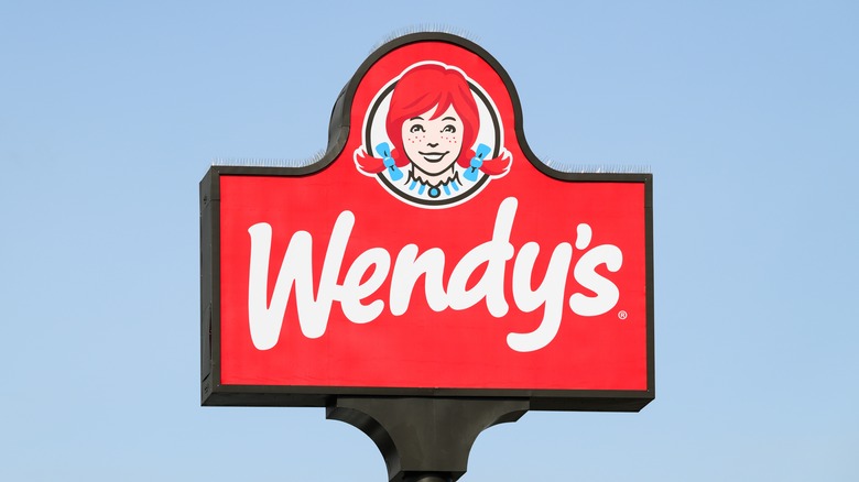 Elevated sign isolated on blue sky for Wendy's fast food restaurant.