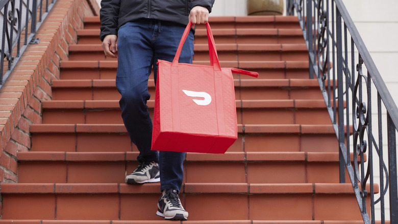 A person carrying a DoorDash bag on stairs