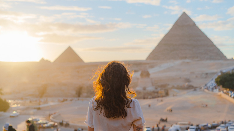 Woman looking at Giza pyramids and Cairo