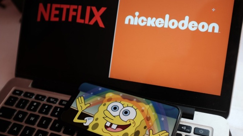 SpongeBob SquarePants on a mobile phone on top of a laptop showing the Netflix and Nickelodeon logos side-by-side.