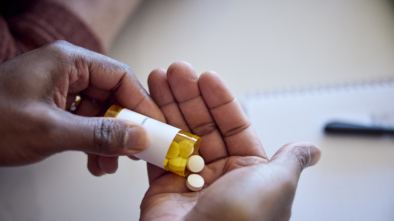 A person pouring medications out of a bottle into their hand