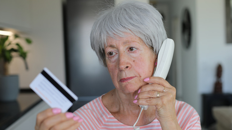 Older woman on a landline holding a credit card