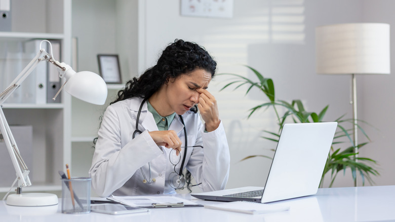 A burnt out doctor at a desk with a laptop