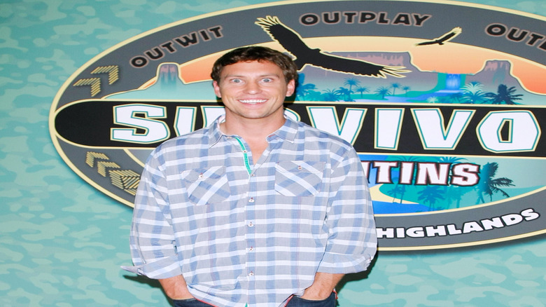 An excited looking Brendan Synnott smiling in front of the "Survivor" logo.