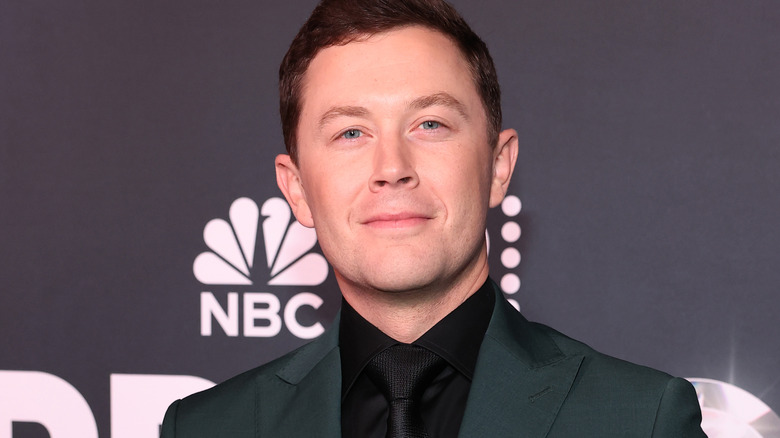 Singer Scotty McCreery wearing black suit, posing on carpet for NBC event