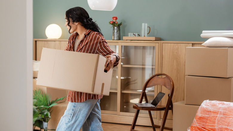 Young woman moving a box out of her old house