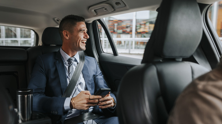 Passenger riding in the back of a taxi with phone in hand