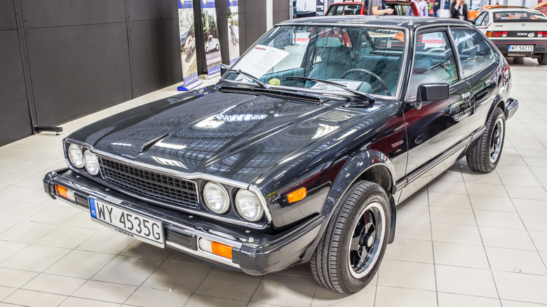 A shiny black 1980 Honda Accord SJ on display in a garage