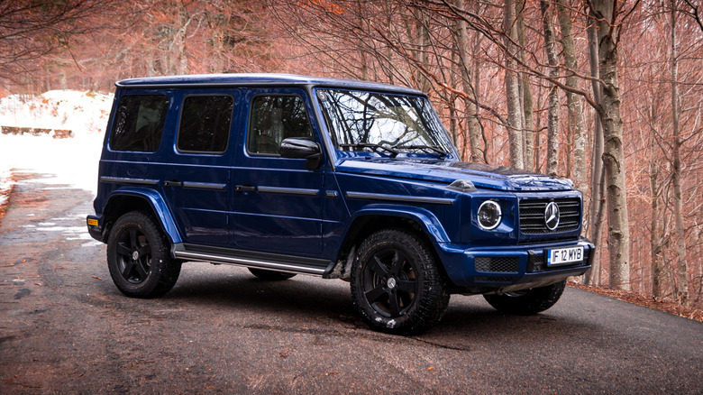 A blue 2021 Mercedes-Benz G-Class on a steep, snowy street in the woods