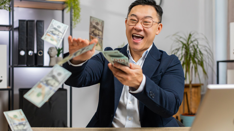 middle aged man happy and throwing cash around house
