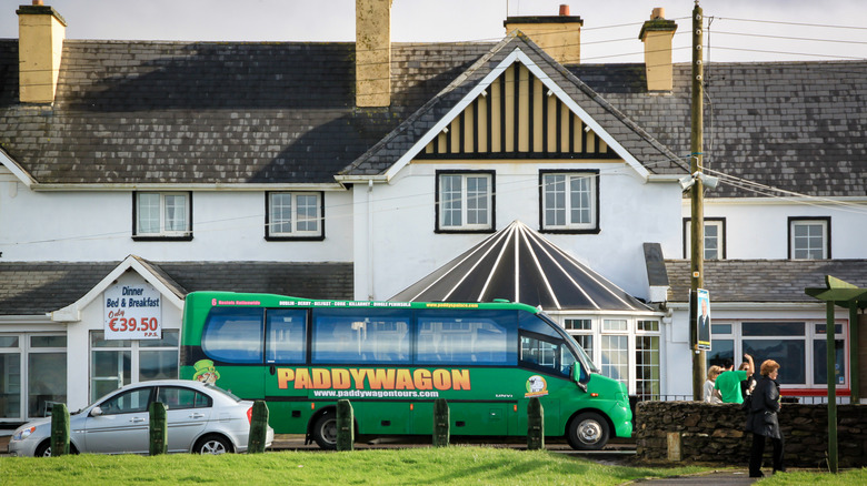 a green Paddywagon tour bus parked outside of a small Irish restaurant