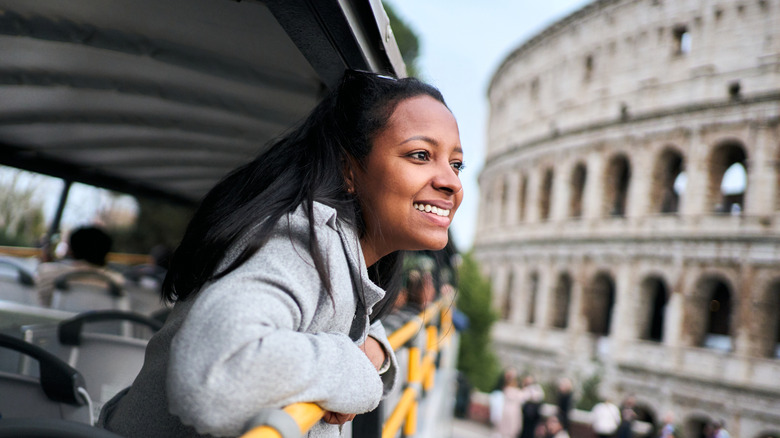 a young woman sits on top of an open bus in Rome
