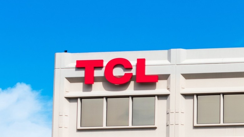 Exterior of a white office building with a red TCL logo near the roofline under a bright blue sky