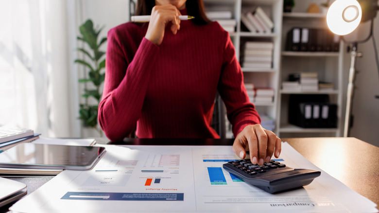 A young investor weighing her options by doing calculations on a calculator