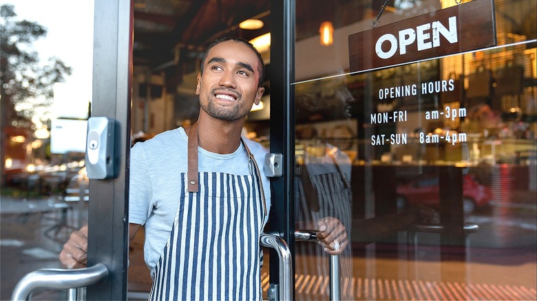 Shopkeeper smiling, opening shop door