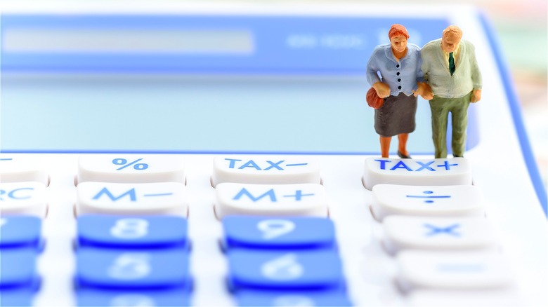 Elderly figurines standing on calculator