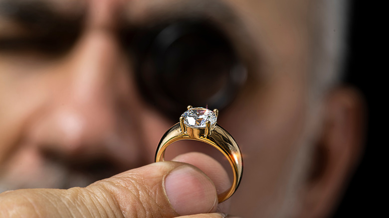 A man closely inspecting a ring.