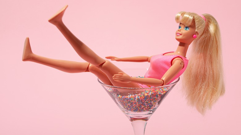 A Barbie doll posed sitting in a martini glass