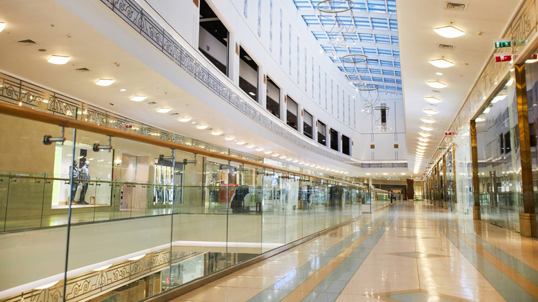 Wide angle background image of multi storey shopping mall interior with glass elements.