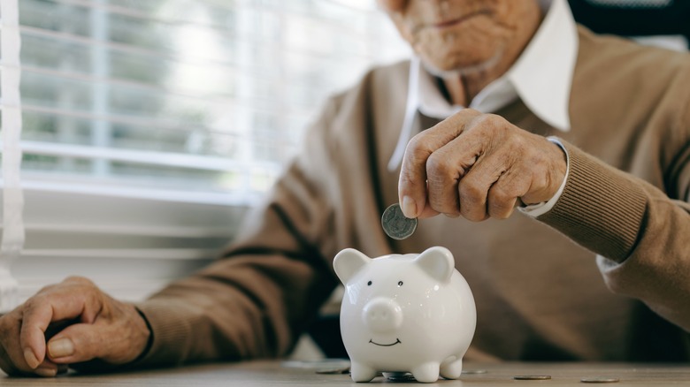 Older person putting coin in a piggy bank