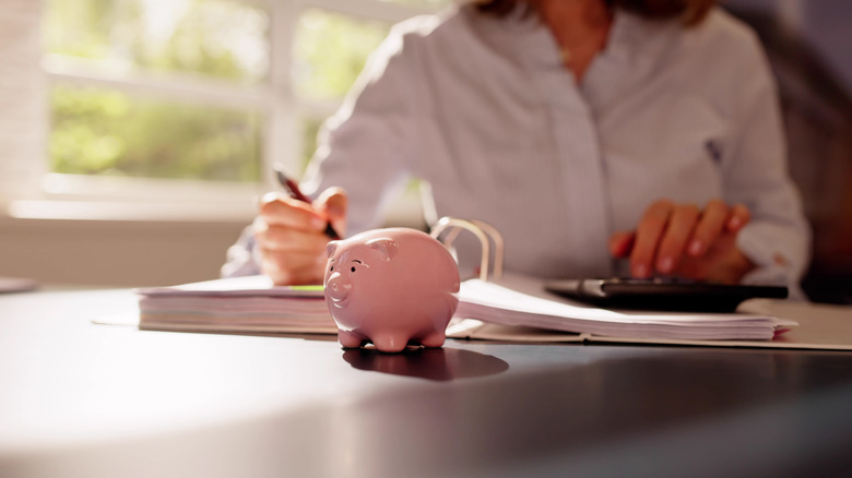Person sitting at table with a binder and piggy bank