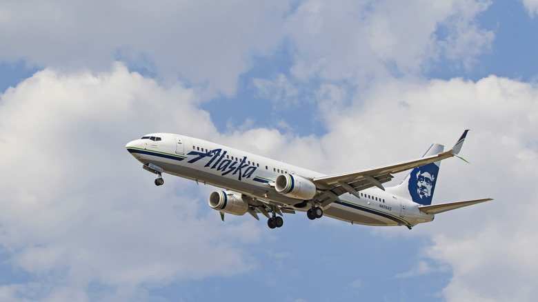 Alaska Airlines jet flying in the sky with clouds