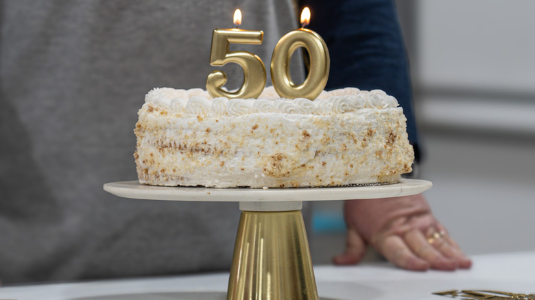 person standing in front of 50th birthday cake