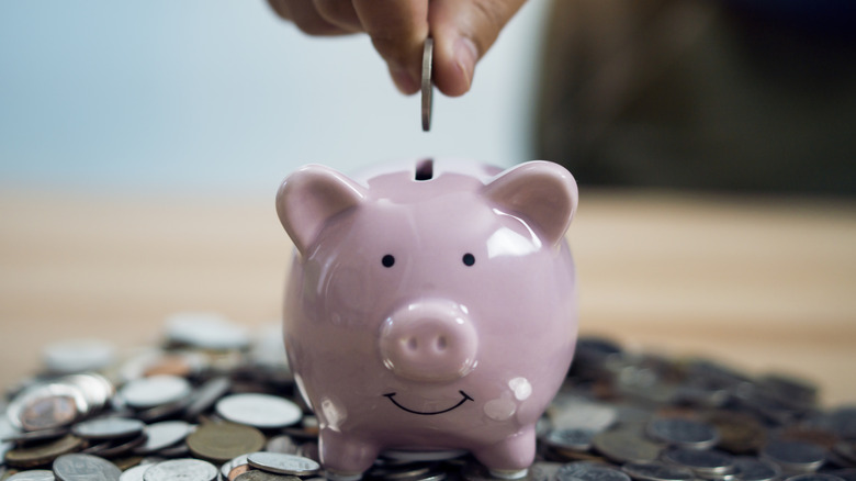 Hand placing coins into piggy bank