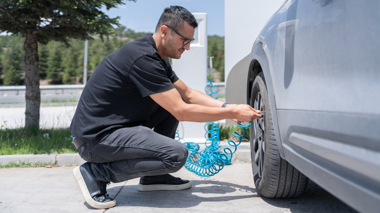 A man checking air pressure in a car tire