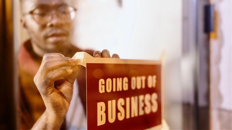 Person putting up "Going Out of Business" sign 