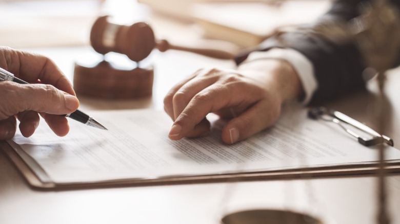 A person signing inheritance forms in a legal setting.