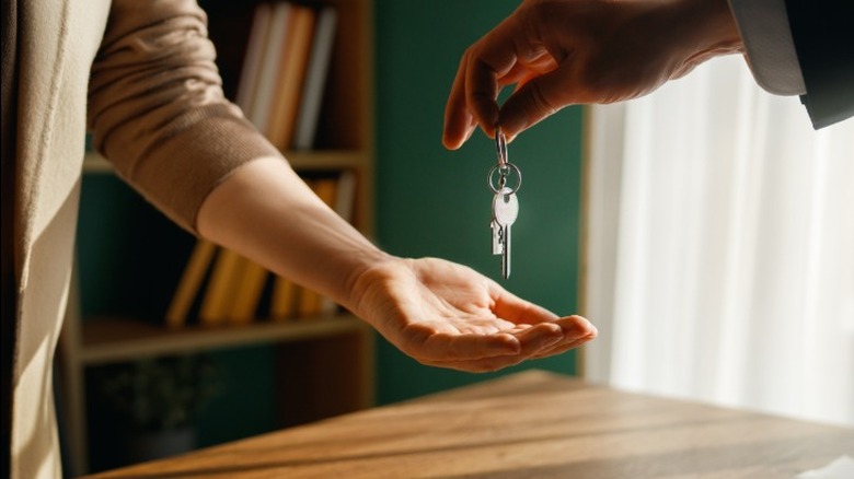 A person holding out their hand receiving keys to an inherited house from a person wearing a suit.