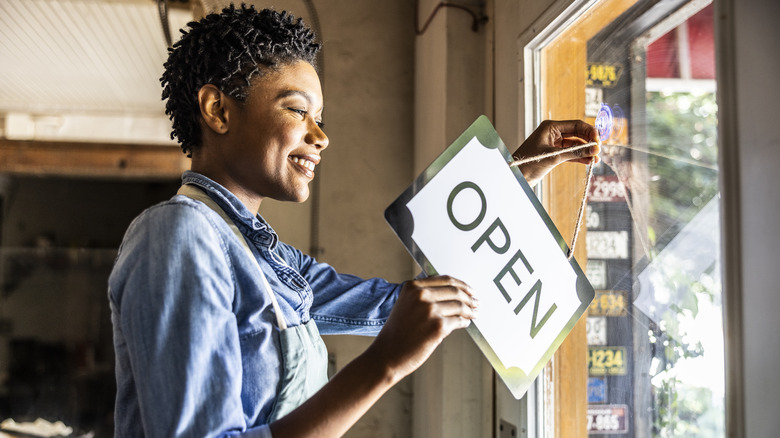 person flipping sign on door to open