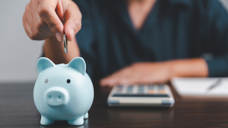 hand putting coin in piggy bank