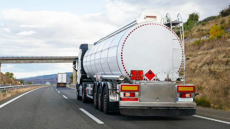 An oil tanker truck travling down a rural highway
