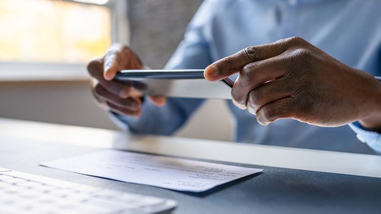A man uses his phone to deposit a check