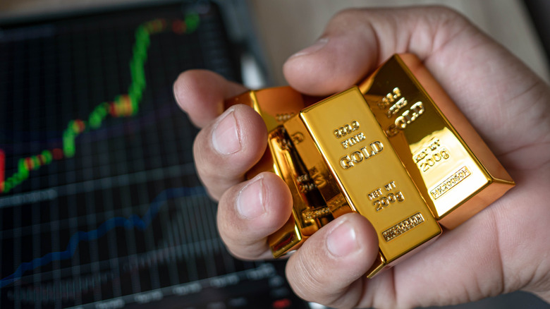 A person holding gold bars with a graph in the background