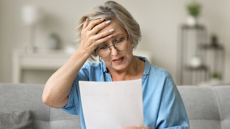 A frustrated woman at home on her couch looking at her credit report.