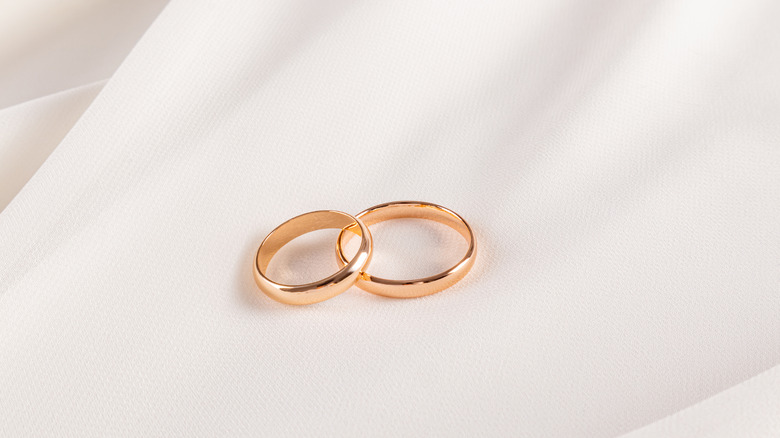 Gold wedding bands on white fabric.