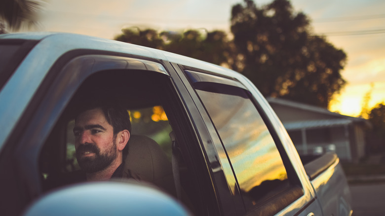 Man driving a truck at twilight.